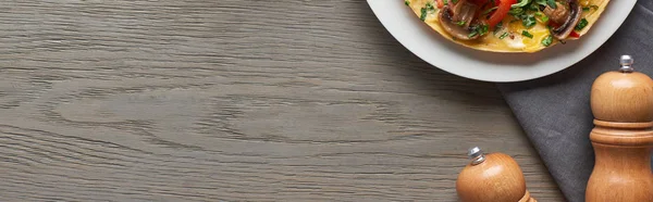 Hausgemachtes Omelett zum Frühstück auf Holztisch mit Pfeffer und Salz — Stockfoto