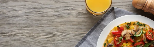 Vista superior de vaso de jugo y tortilla casera con verduras para el desayuno en mesa de madera - foto de stock