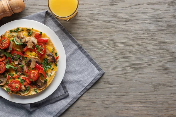 Draufsicht auf Glas Saft und hausgemachtes Omelett mit Gemüse zum Frühstück auf Holztisch mit Serviette — Stockfoto