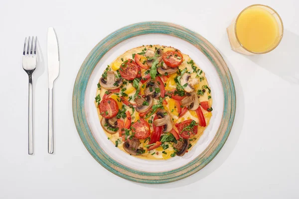 Vista dall'alto di gustosa frittata a colazione su tavolo bianco con succo di frutta, forchetta e coltello — Foto stock