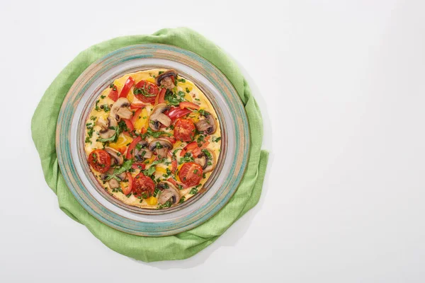 Vista superior da placa com omelete saboroso com tomates e cogumelos para o café da manhã na mesa branca com guardanapo — Fotografia de Stock