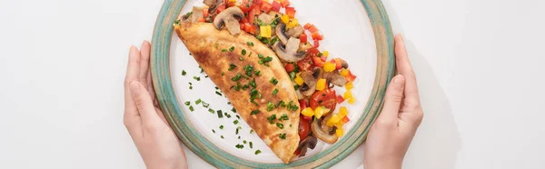 Cropped view of woman holding plate with homemade wrapped omelet with vegetables — Stock Photo