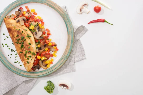 Vue du dessus de la plaque avec omelette enveloppée maison délicieuse avec des légumes sur table blanche avec des ingrédients frais — Photo de stock