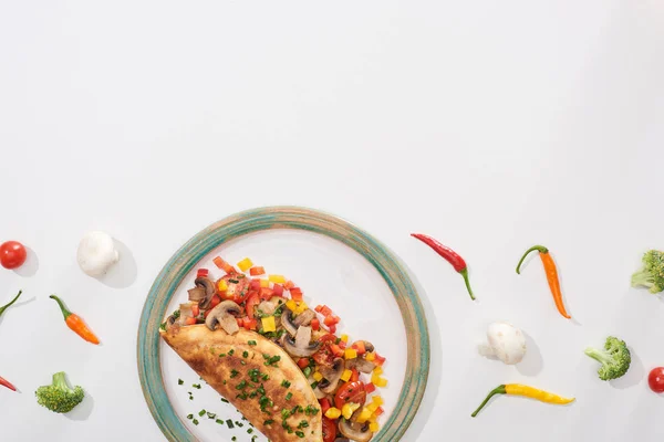 Vista superior de la deliciosa tortilla envuelta con verduras en el plato con chiles frescos y brócoli - foto de stock