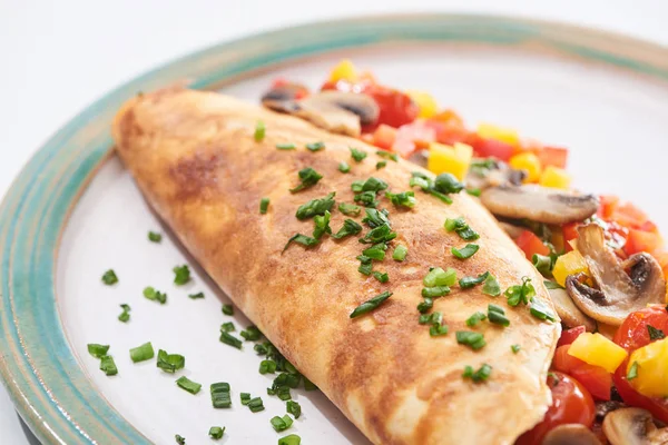 Gros plan d'omelette enveloppée maison avec champignons, tomates, légumes verts et poivrons dans l'assiette — Photo de stock