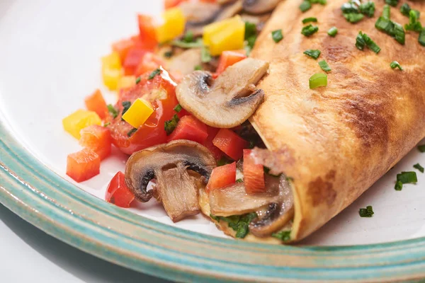 Close up of yummy wrapped omelet with mushrooms and peppers on plate — Stock Photo