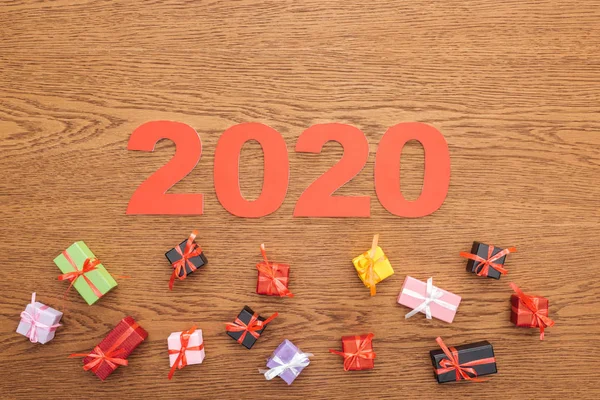 Верхний вид бумаги 2020 номера вблизи небольших декоративных подарочных коробок на деревянном фоне — стоковое фото