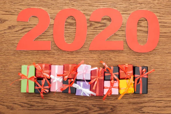 Top view of paper 2020 numbers near small decorative gift boxes on wooden background — Stock Photo