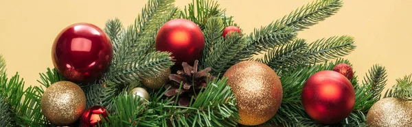 Top view of christmas tree branch with baubles on yellow background, panoramic shot — Stock Photo