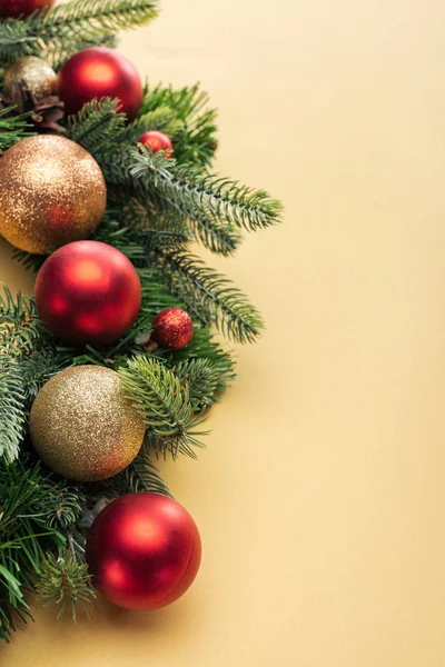 Christmas tree branch with baubles on yellow background — Stock Photo