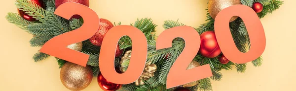 Draufsicht auf Papier 2020 Zahlen in der Nähe von Weihnachtsbaum Zweig mit Kugeln auf gelbem Hintergrund — Stockfoto