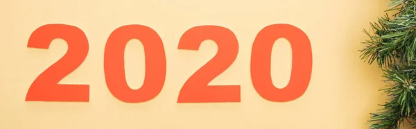 Top view of paper 2020 numbers near christmas tree branch on yellow background, panoramic shot — Stock Photo