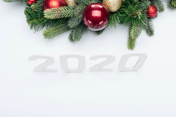 Верхний вид бумаги 2020 номера возле елки венок с безделушками на белом фоне — стоковое фото