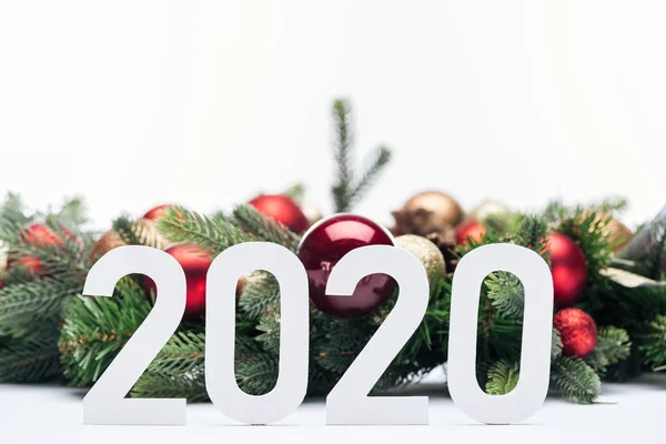 Paper 2020 numbers near Christmas tree wreath with baubles isolated on white — Stock Photo