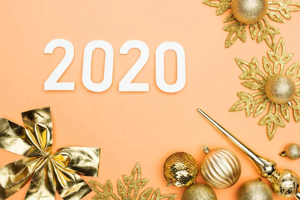 Vista dall'alto dei numeri bianchi 2020 vicino alla decorazione natalizia dorata su sfondo arancione — Foto stock