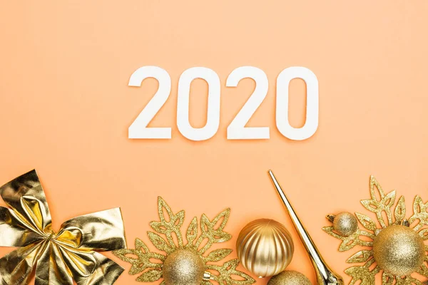 Draufsicht auf weiße Zahlen 2020 und goldene Weihnachtsdekoration auf orangefarbenem Hintergrund — Stockfoto