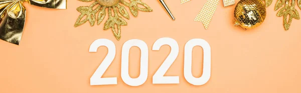 Top view of white 2020 numbers near golden christmas decoration on orange background, panoramic shot — Stock Photo