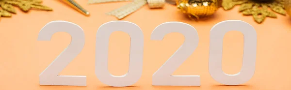 White 2020 numbers near golden christmas decoration on orange background, panoramic shot — Stock Photo