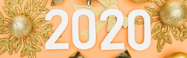 Vista superior de los números blancos 2020 en la decoración de Navidad de oro sobre fondo naranja, plano panorámico - foto de stock
