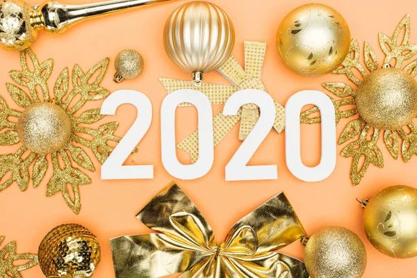 Vista superior de los números blancos 2020 en la decoración de Navidad de oro sobre fondo naranja - foto de stock