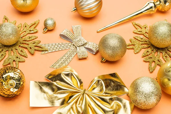 Goldener Weihnachtsschmuck auf orangefarbenem Hintergrund — Stockfoto
