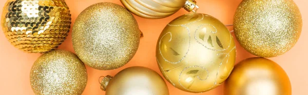 Top view of golden shiny baubles on orange background, panoramic shot — Stock Photo