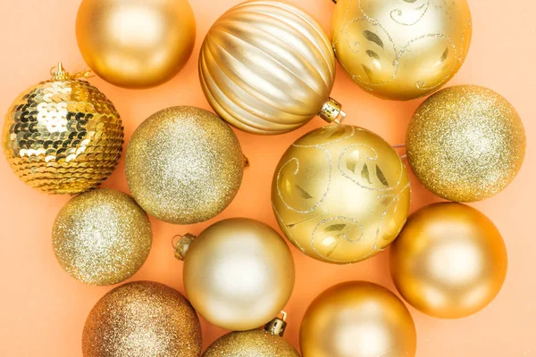 Top view of golden shiny baubles on orange background — Stock Photo