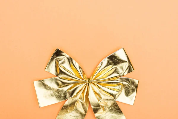 Top view of golden shiny decorative bow on orange background with copy space — Stock Photo