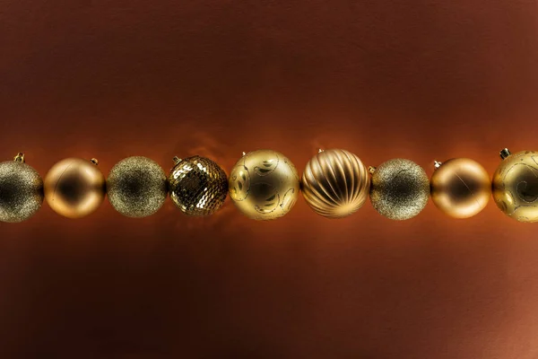 Top view of golden christmas baubles in row on dark background — Stock Photo