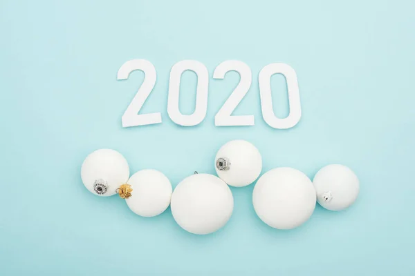Top view of white 2020 numbers near Christmas baubles on light blue background — Stock Photo