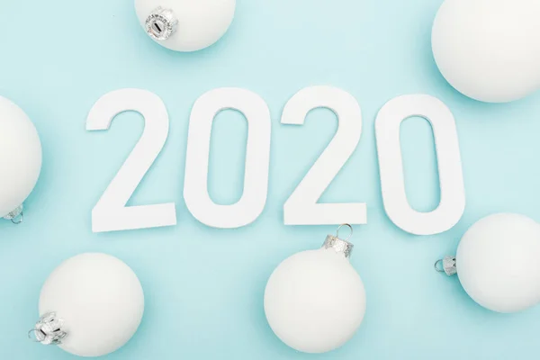 Top view of white 2020 numbers near Christmas baubles on light blue background — Stock Photo