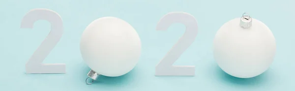 Chiffres blancs 2020 près de Boules de Noël sur fond bleu clair, panoramique — Photo de stock