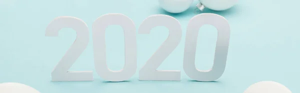 Weiße Zahlen 2020 in der Nähe von Christbaumkugeln auf hellblauem Hintergrund, Panoramaaufnahme — Stockfoto
