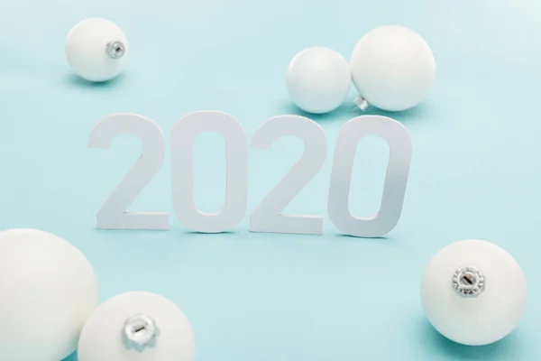 Números blancos 2020 cerca de bolas de Navidad sobre fondo azul claro - foto de stock