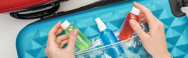 Panoramic shot of woman holding bright bottles with liquids — Stock Photo