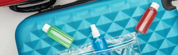 Panoramic shot of bright bottles with liquids on travel bag — Stock Photo