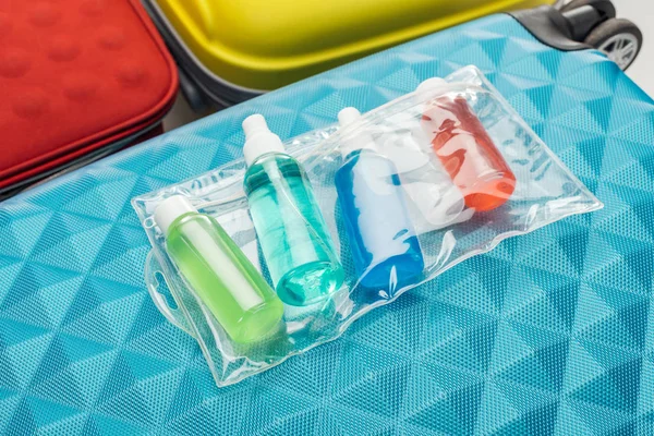 Bright bottles with liquids and cosmetic bag on travel bag — Stock Photo