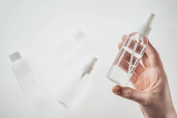 Vue recadrée de la femme tenant bouteille avec du liquide sur fond blanc — Photo de stock