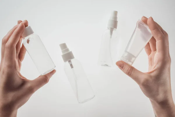 Vista recortada de la mujer sosteniendo botellas con líquidos sobre fondo blanco - foto de stock