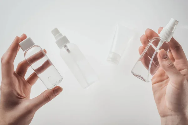 Cropped view of woman holding bottles with liquids on white background — Stock Photo