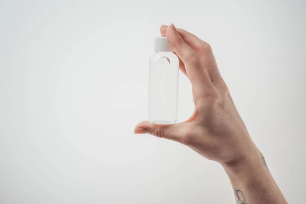 Cropped view of woman holding bottle with liquid on white background — Stock Photo