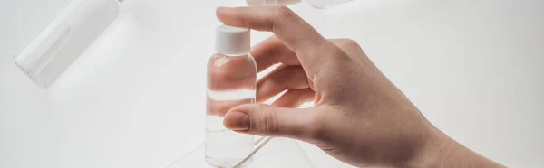 Plan panoramique de la femme tenant bouteille avec du liquide sur fond blanc — Photo de stock