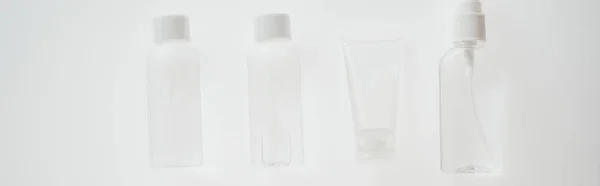 Tiro panorâmico de garrafas e tubo com líquidos sobre fundo branco — Fotografia de Stock