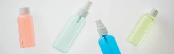 Panoramic shot of colorful bottles with liquids on white background — Stock Photo