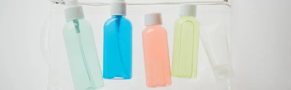 Tiro panorâmico de garrafas coloridas com líquidos em saco cosmético no fundo branco — Fotografia de Stock