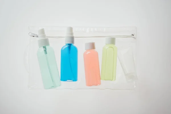 Botellas de colores con líquidos en bolsa de cosméticos sobre fondo blanco - foto de stock