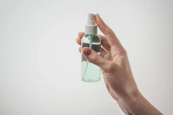 Vista recortada de la mujer sosteniendo botella con líquido sobre fondo blanco - foto de stock