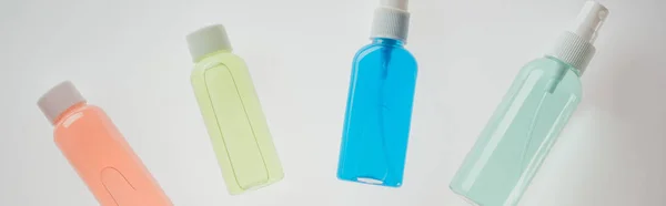 Plano panorámico de botellas de colores con líquidos sobre fondo blanco - foto de stock
