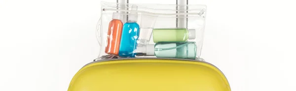 Панорамний знімок дорожньої сумки з косметичним пакетом з барвистими пляшками з рідинами ізольовані на білому — стокове фото
