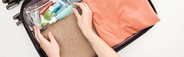 Panoramic shot of woman packing travel bag on white background — Stock Photo